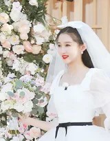 关晓彤低头轻抚裙摆，珍珠头饰与静谧神情交织出古典韵味