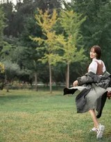 张嘉倪手持一片绿叶轻遮眼前，透过缝隙望向镜头，眼神 playful 而清澈，充满少女趣味