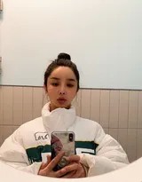 一抹明媚笑容绽放在河莉秀脸上，背景温暖，传递出历经风雨后依然拥抱生活的乐观精神。