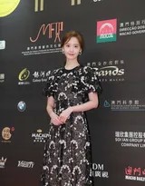 林允儿轻抚秀发，黑色蕾丝袖下的手臂线条纤细，她回眸浅笑，身后的光影为她勾勒出一圈温柔的光晕