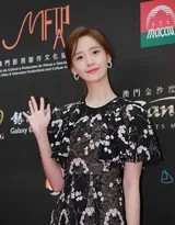 林允儿身着黑色蕾丝长裙，在灯光下微微侧首，精致的侧颜与颈线如天鹅般优雅，甜美笑容中眼波流转