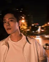 肖战侧身倚靠在天桥栏杆上，月光与远处车流在他轮廓上镀了一层清辉，眼神望向城市深处，静谧而深远