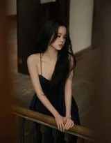 欧阳娜娜身着黑色低胸吊带裙倚坐，微卷长发披肩，姿态放松而惬意，柔和光线映衬出温柔恬淡的侧颜