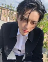 吴亦凡侧身回眸，阳光勾勒出清晰的轮廓，他嘴角带有一丝若有若无的笑意，仿佛与这座古老城市进行着无声对话