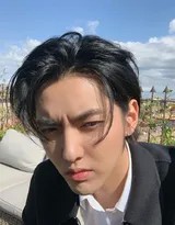 吴亦凡身着深色T恤，戴着墨镜，在罗马炽热的阳光下微微仰头，背景是古老的石墙与蓝天