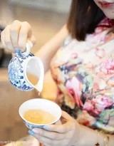绮里嘉跪坐于茶席前，俯身准备沏茶，蕾丝修饰的旗袍后背设计宛如一幅精致画作，她的长发如瀑垂下，姿态虔诚而优雅