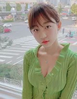 圆润少女坐于落地窗边，手持书籍，神情专注