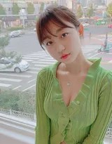 少女回头微笑，绿衣在光影中泛起柔和光泽
