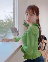 绿衣少女站立窗前，阳光透过玻璃洒在脸上，笑容自然不做作