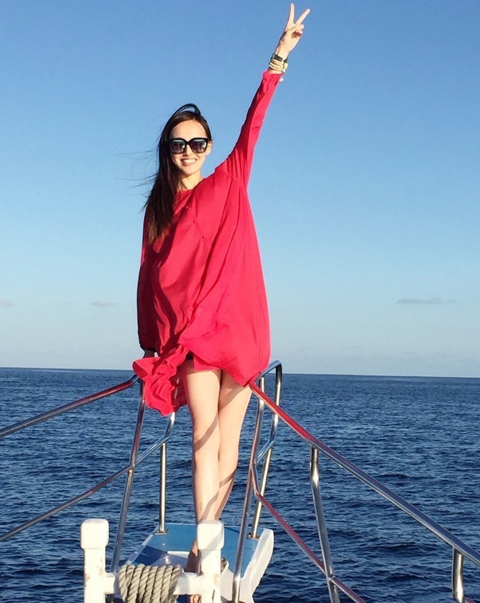 海风撩起唐嫣的波浪卷发，她立于木梯旁，指尖小花戒指点缀，尽显不经意的浪漫风情