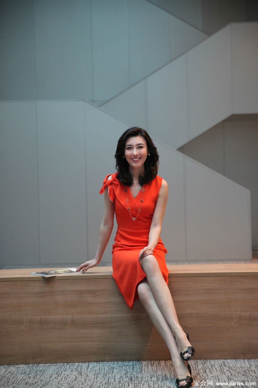 李红身着黑色礼服侧身站立，灯光勾勒出其优雅的身姿曲线与专注的侧颜