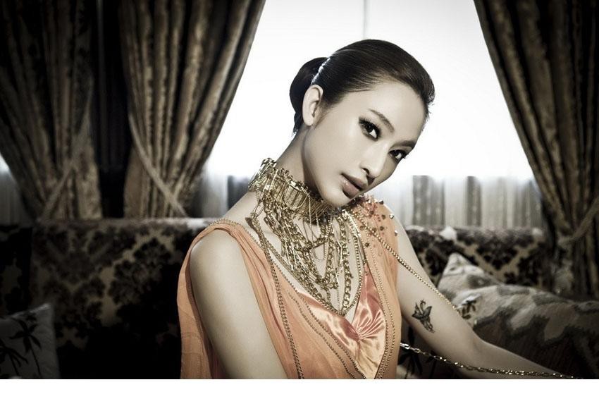 张俪身着金色礼服立于光影交界，宛若文艺复兴画作中走出的女神
