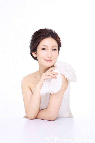 秦海璐身穿深色修身礼服，在简约背景前展露温婉笑容，尽显柔和魅力