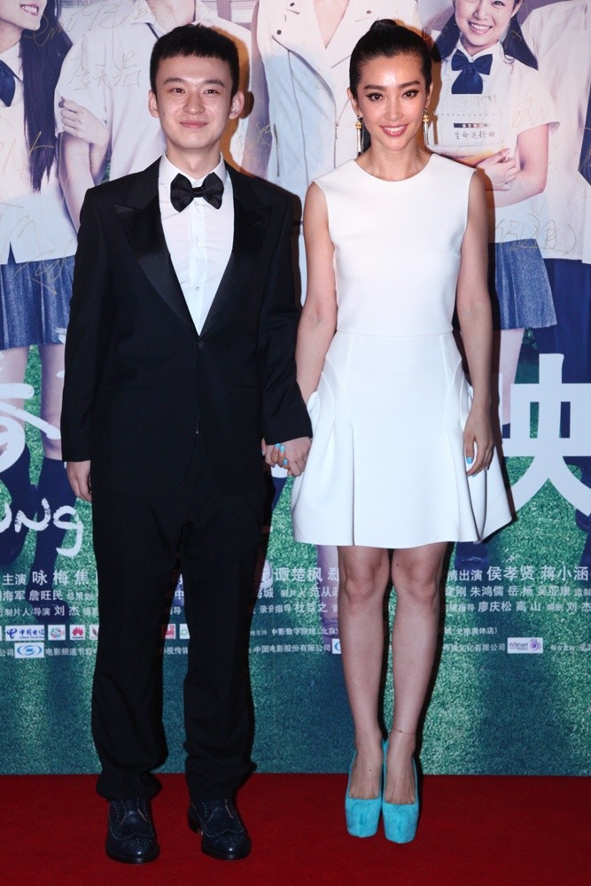 镜头特写李冰冰的精致侧颜与肩颈线条，黑色礼服的薄纱披肩轻笼肌肤，珍珠耳坠点缀其间，尽显含蓄的性感。