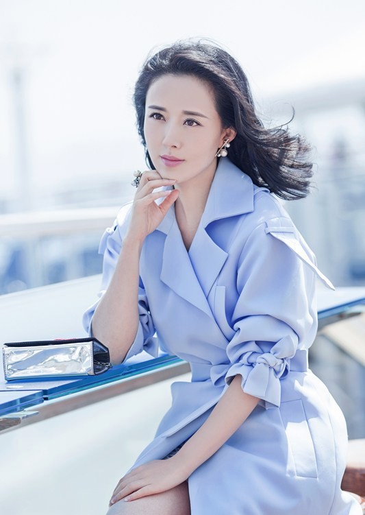 倚靠木桌托腮凝思，浅色穿搭与静谧秋意相得益彰