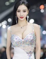 吴春怡侧身倚靠流线型跑车，曲线玲珑，丰满身材在银色礼服下若隐若现，眼神自信而迷人