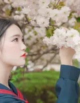 少女在草地上仰拍，制服领结整齐，蓝天白云背景突显自由气息