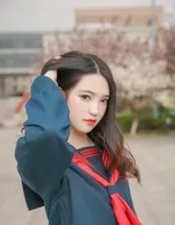 阳光下制服少女在草地持相机自拍，笑容灿烂如花，青春洋溢