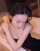 俯视视角下，她如水中精灵般舒展，长发散开如海藻，黑色吊带裙的领口设计在光影中勾勒出迷人的阴影，构图充满宁静的张力。