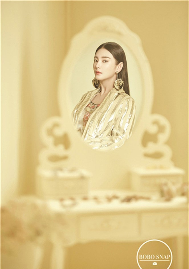 张雨绮身着橘粉色系服饰置身浅色背景前，妆容精致眼神自信，绽放如夏日蜜桃般的甜酷笑容