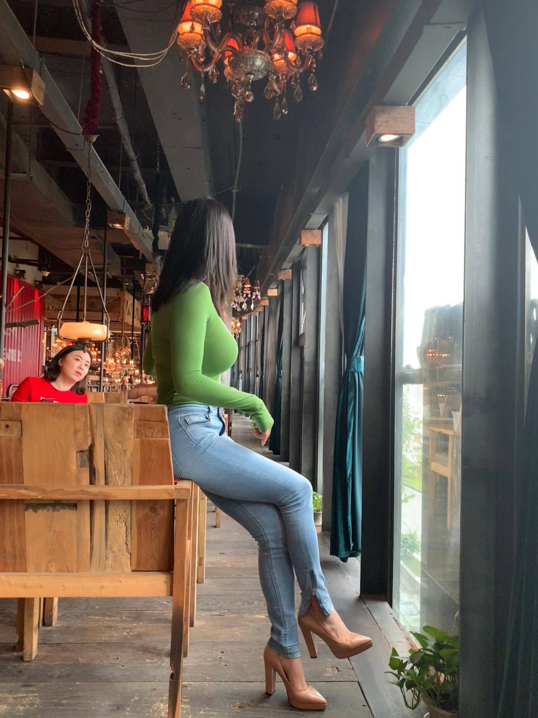 女性身穿白色短款上衣与浅色牛仔裤，侧身站立凸显身体玲珑曲线