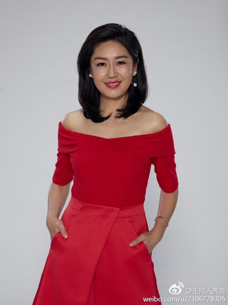 齐奇坐在高脚椅上，双腿交叉展现优雅线条，肉色丝袜在聚光灯下如第二层肌肤般贴合