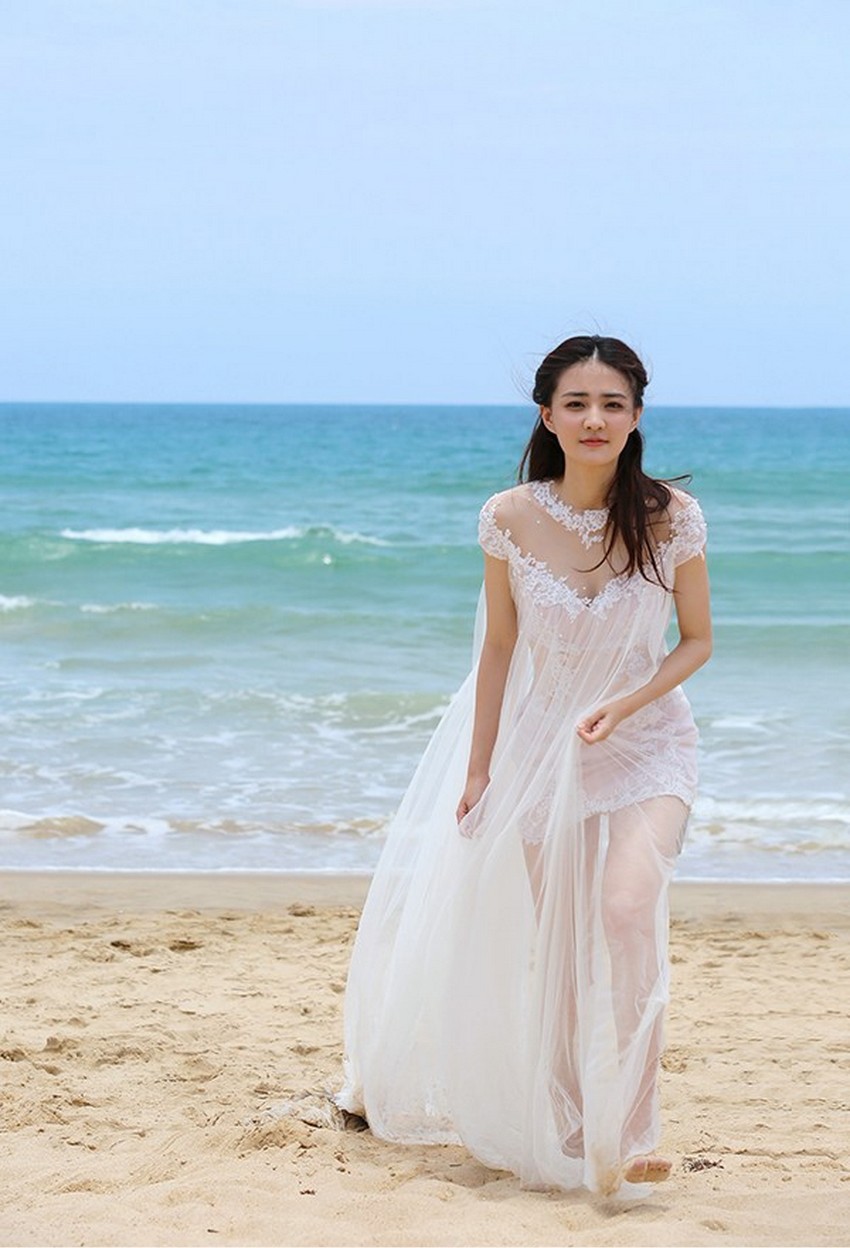 徐璐轻提裙裾微步浅滩，浪花在脚边绽开晶莹花朵，画面灵动充满生机