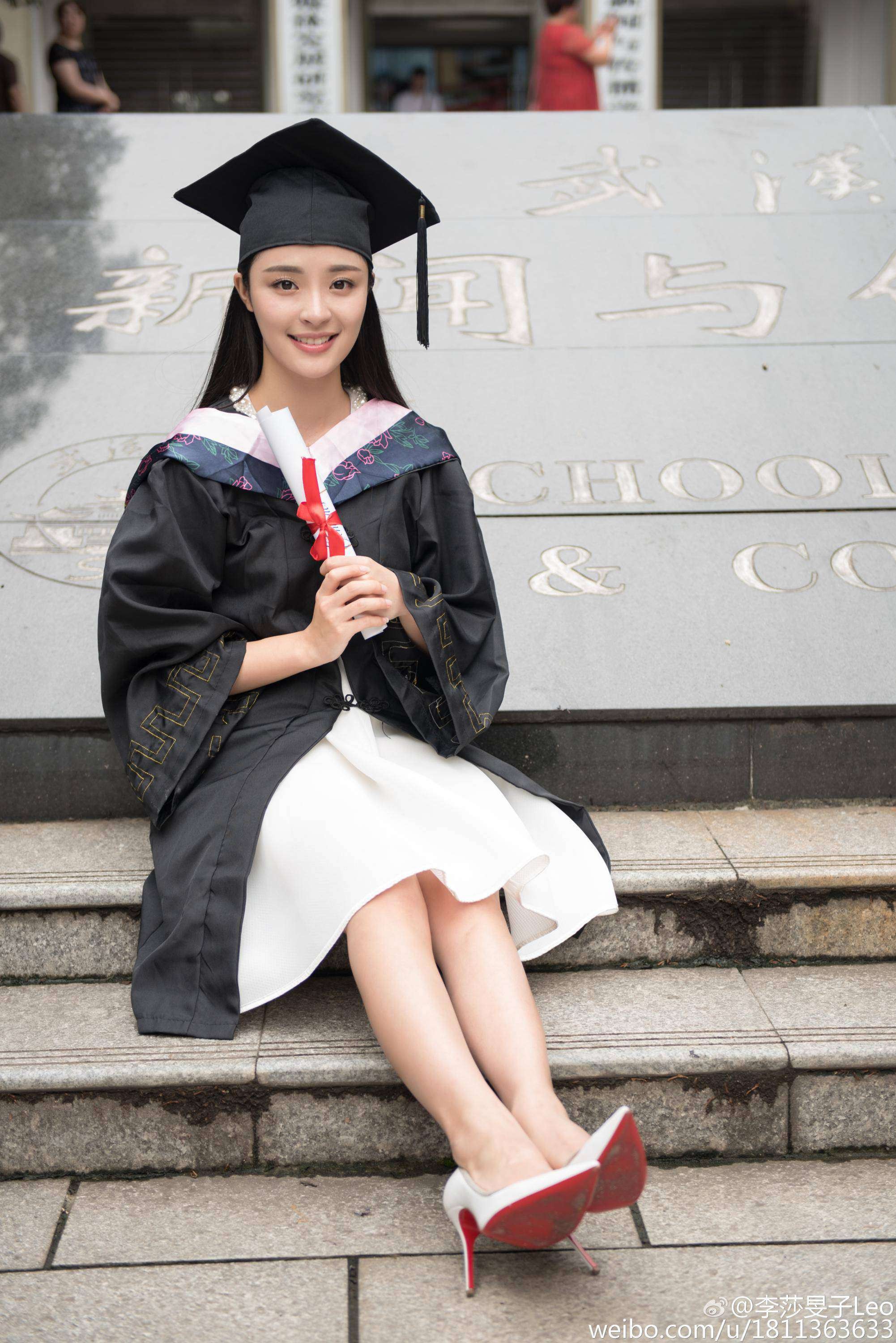 李莎旻子身穿黑色学位服手持毕业证书于大学校门前展露灿烂笑容